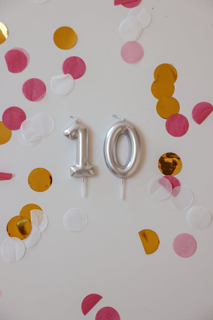 Vibrant birthday decoration with silver number 10 candles and colorful confetti on a white background.